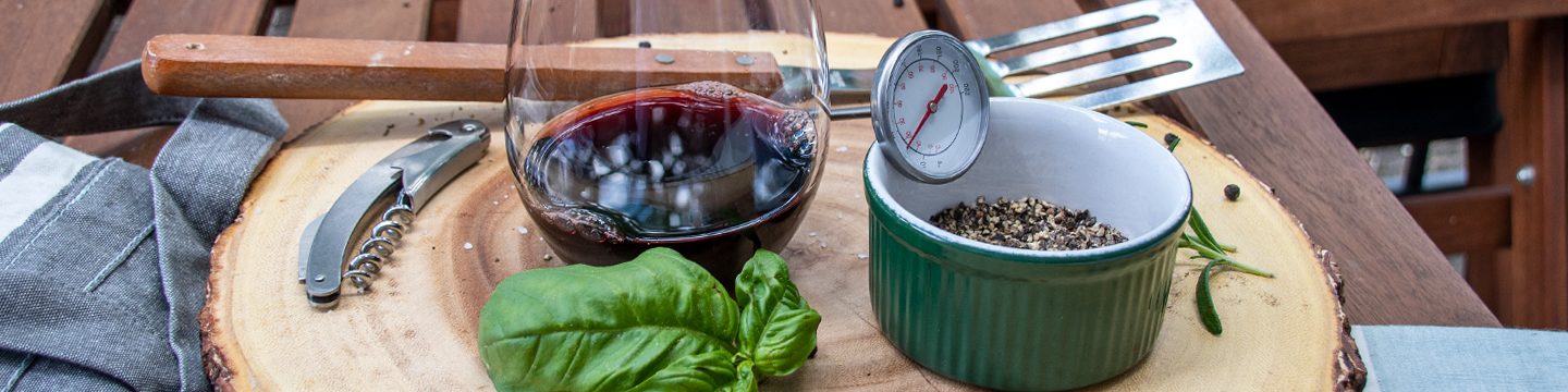 Glass of red wine, basil leaf, timer, and bowl of spices ready to bbq