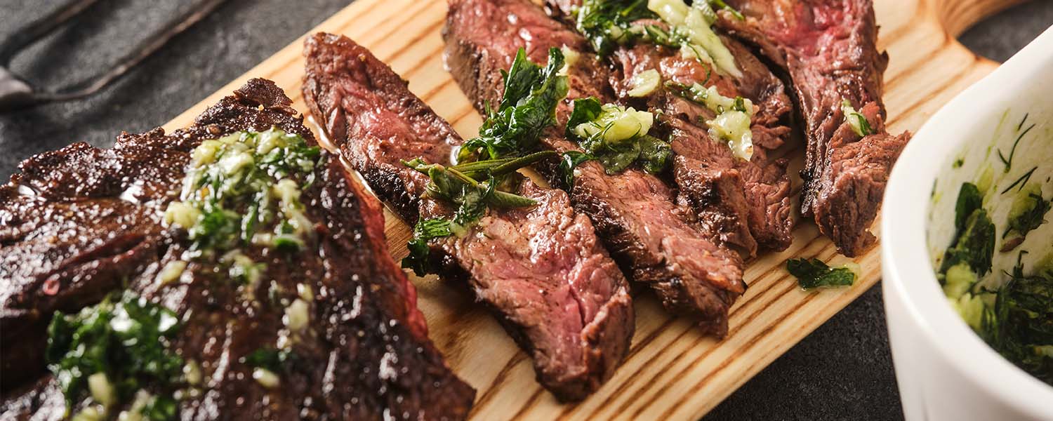 A platter of seared steak that is cut against the grain and served with chimichurri sauce. A classic dinner recipe 