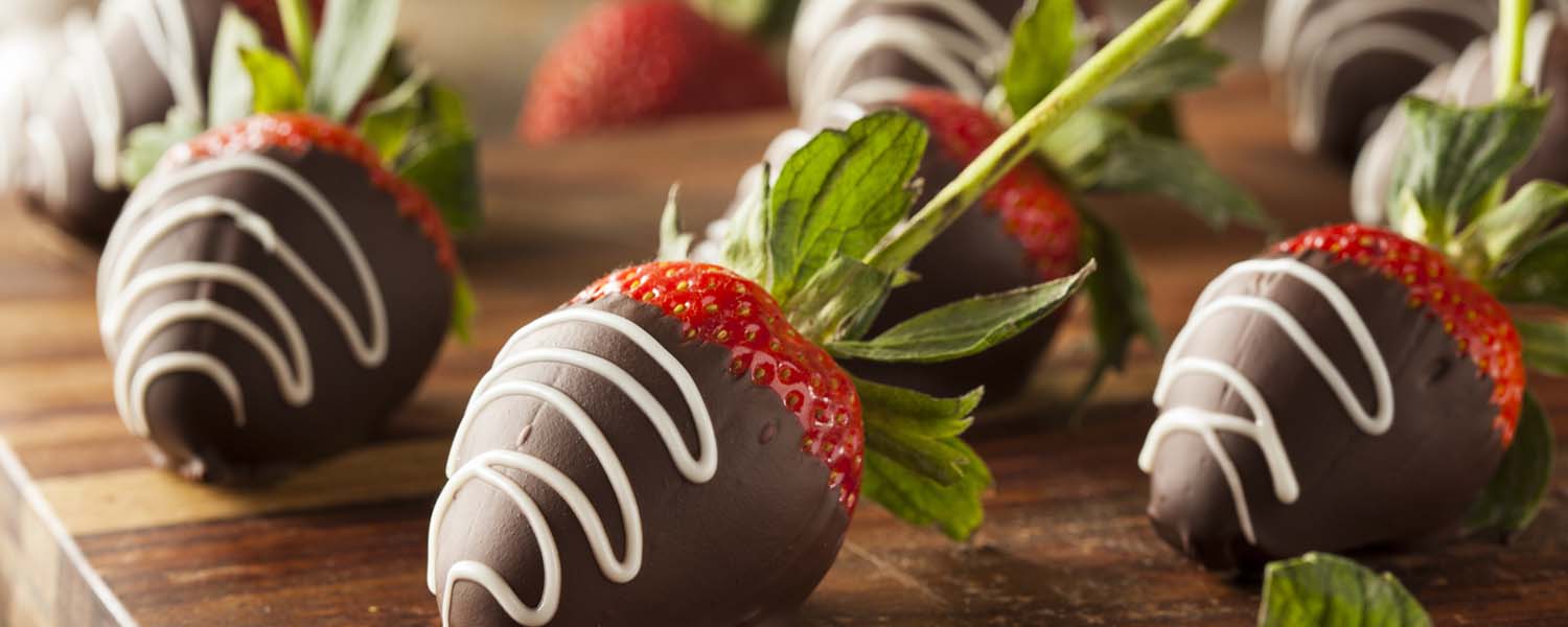 A board of chocolate-covered strawberries with white chocolate drizzle on them. A dessert recipe to enjoy after dinner.