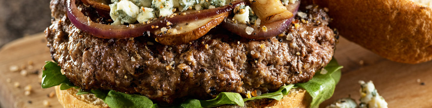 Juicy hamburger with onion and mushroom topping with blue cheese crumbles.