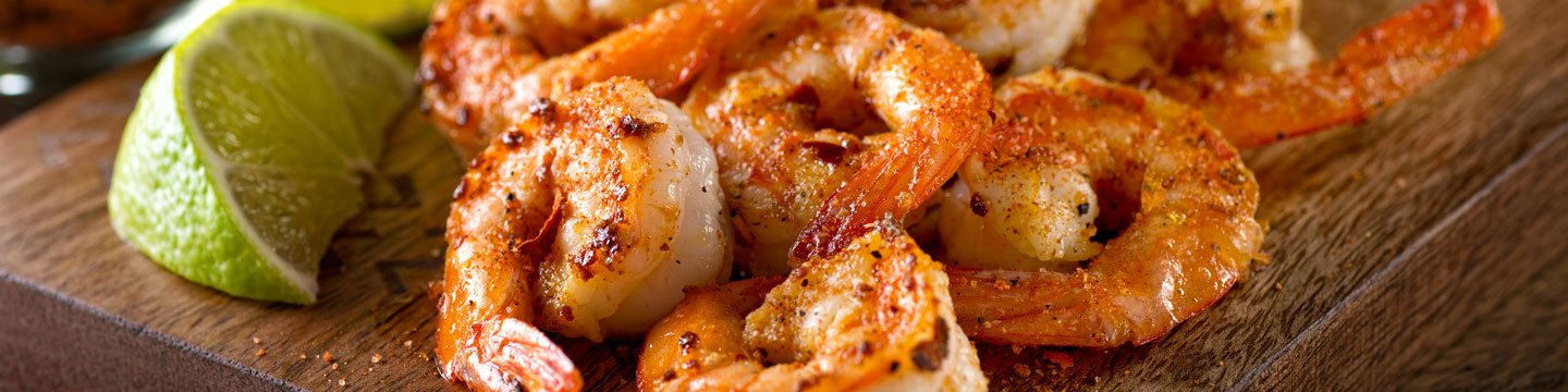 Cajun-seasoned shrimp on a wooden board with a lime wedge