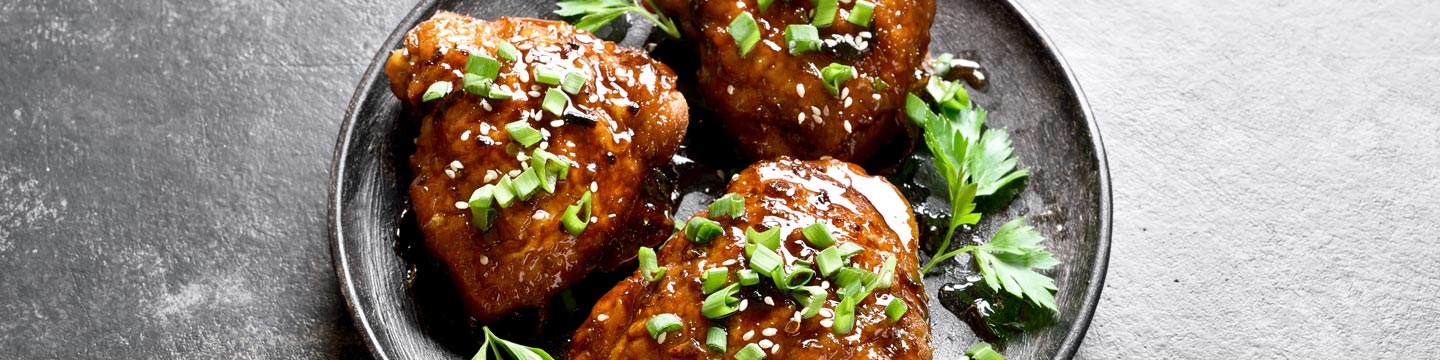 Honey-soy glazed chicken thighs with fresh green onions and sesame seeds sprinkled on top.