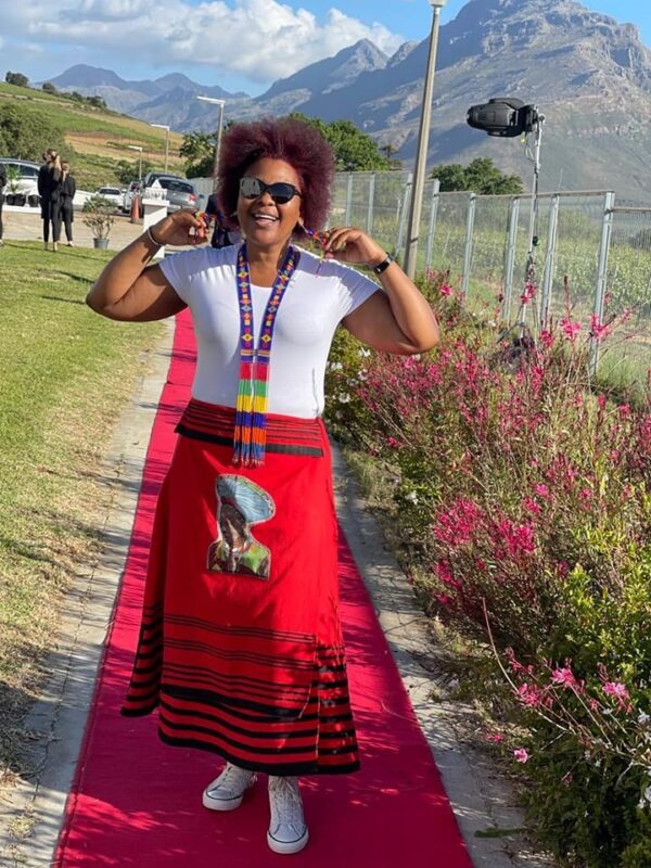 Nondumiso Pikashe of Ses'fikile Wines walks a red carpet wearing a traditional red skirt.